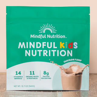 A green resealable pouch of Mindful Kids Nutrition cocoa mix with a picture of a chocolate beverage and text highlighting 14 vitamins/minerals, 11 organic fruits/vegetables, and 8g protein per serving.