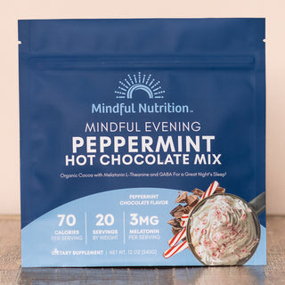 A pouch of Mindful Nutrition's Mindful Evening Peppermint Hot Chocolate Mix with the product's details visible on the front. The packaging is predominantly blue with white and red text, and an image of the cocoa mix with peppermint candy pieces.