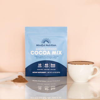Relaxing evening setup with Mindful Nutrition cocoa mix for sleep, featuring cocoa pouch, ceramic mug, and cocoa powder on a reflective surface