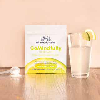 A resealable pouch of GoMindfully drink mix with Lemon Lime flavor, with a glass and scoop.
