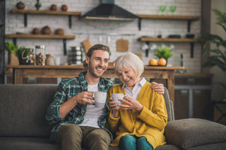 Man and woman sitting on a couch in a cozy living room, holding mugs.
